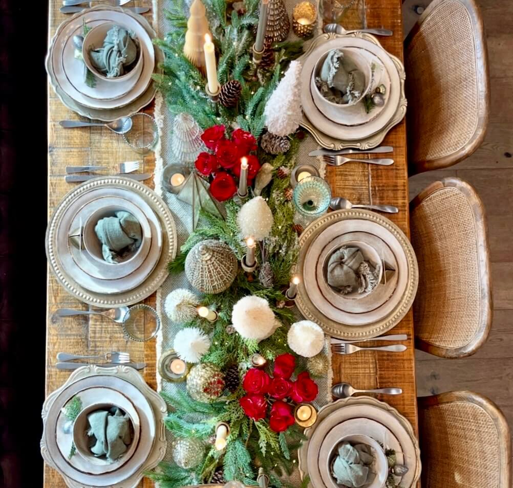 Christmas tablescape with fresh flowers and greenery centerpiece on a decorated holiday table.